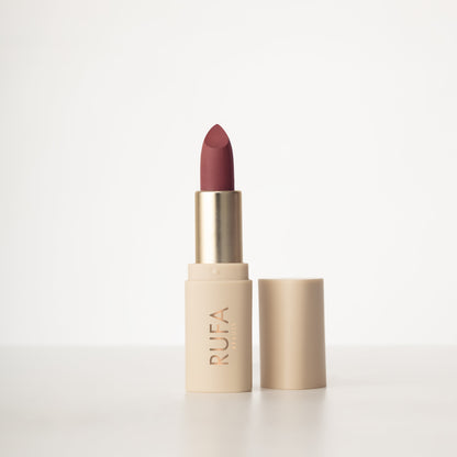 A matte lipstick in a bullet container, with the brand name 'RUFA' inscribed on it. The color of the lipstick is dark muted pink shade